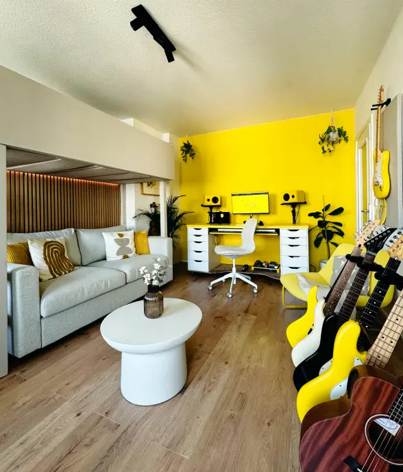 Yellow chair beside a wall of mounted guitars and a guitar stand